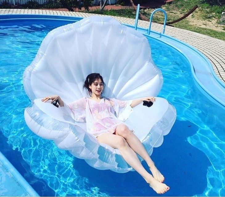 chica recostada en un flotador con forma de concha