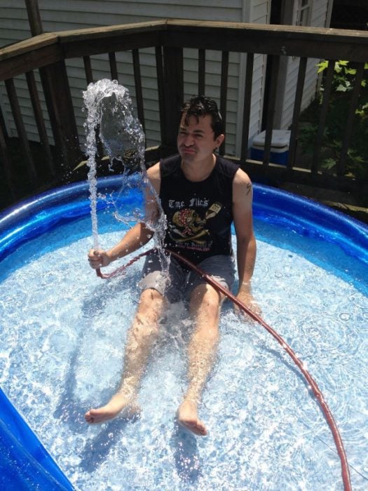 Hombre jugando con una manguera mientras está dentro de una piscina portatil 