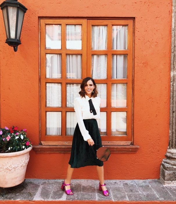 Yuya usando una falda negra y blusa blanca con zapatos rosas