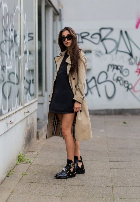 Chica usando un vestido negro con una gabardina de color café 