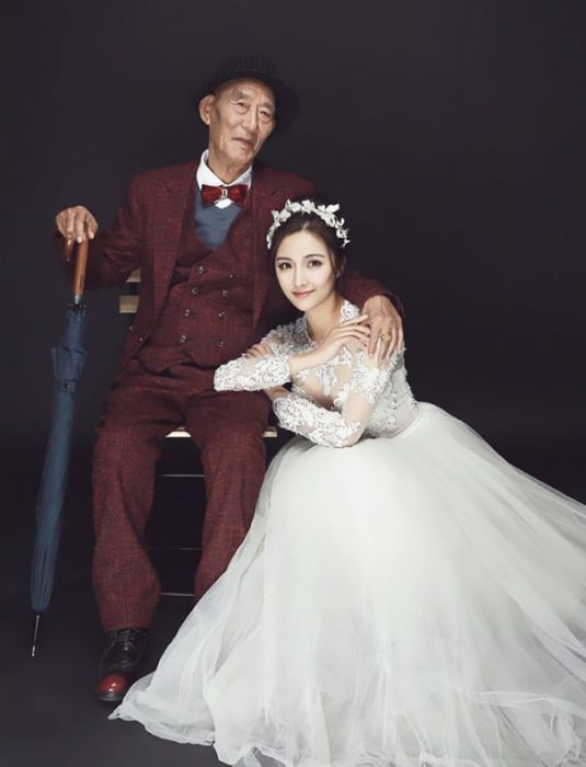 Chica vestida de novia posado junto a su abuelo 