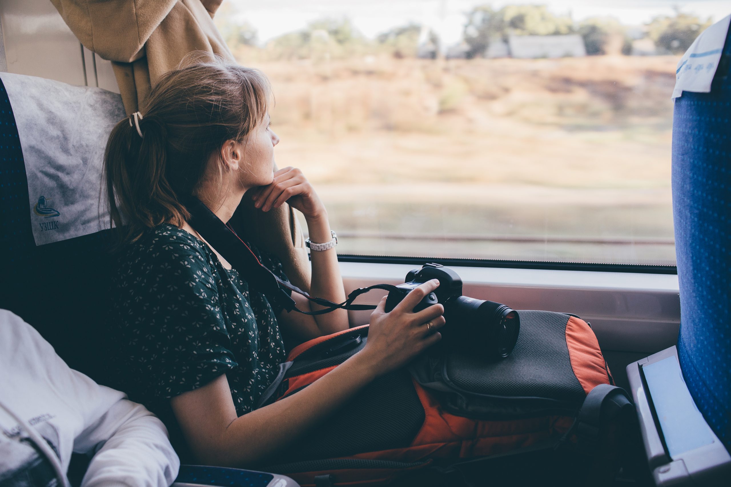 Chica sosteniendo su cámara y viajando en un tren 