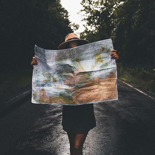 Chica mirando un mapa mientras está en medio de la carretera 