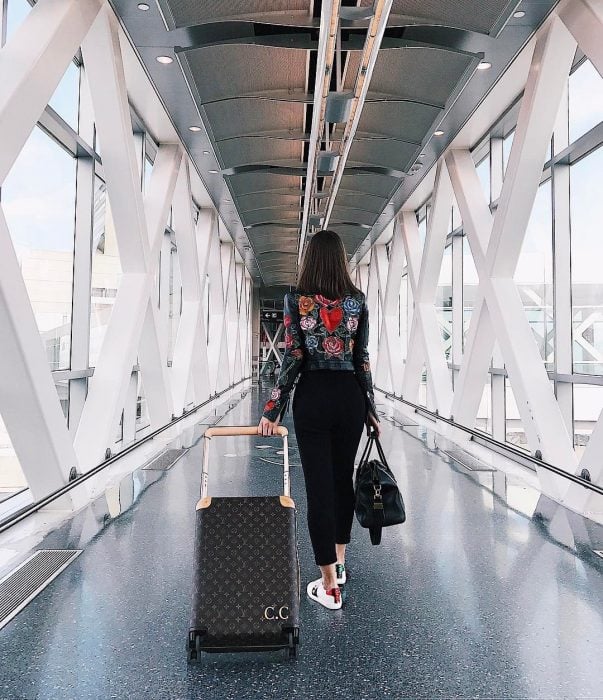 Chica caminando con su maleta mientras va en el aeropuerto 