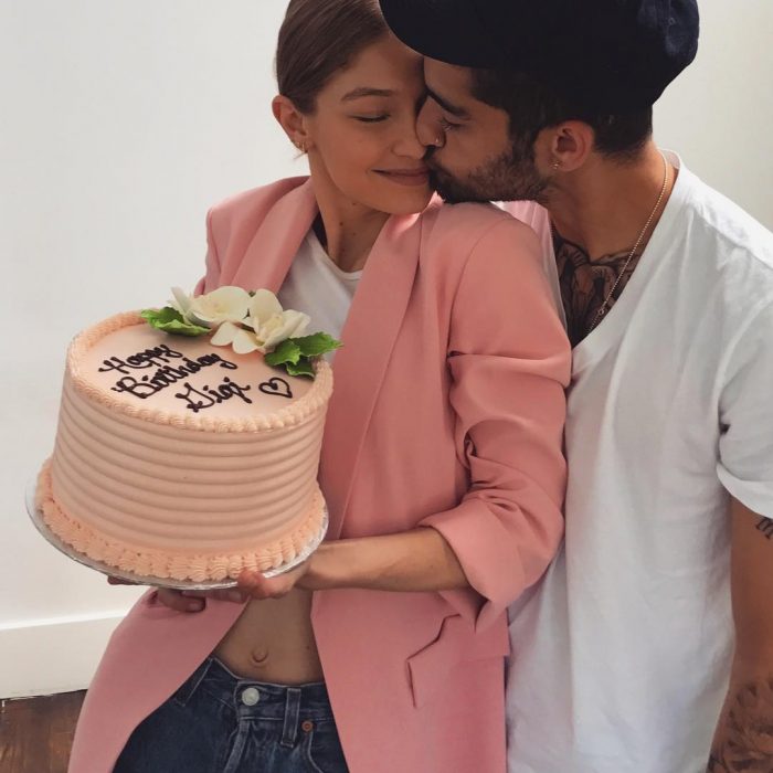 Gigi Hadid sosteniendo un pastel de cumpleaños mientras Zayn la besa