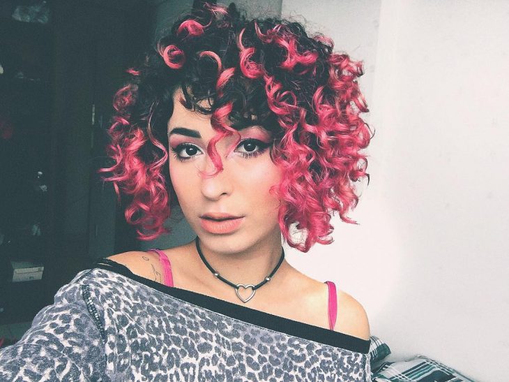 Chica con el cabello chino usando un tono rosa chicle 