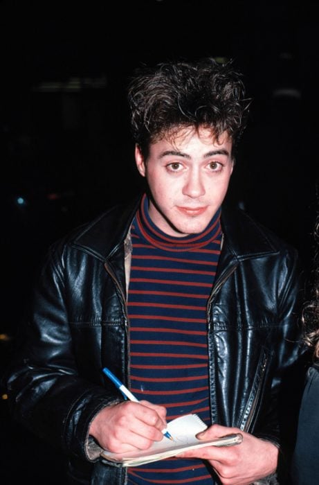 Chico con camisa a rayas, chaqueta de cuero negro, cabello oscuro, escribiendo en una libreta y mirando de frente a la cámara, Robert Downey Jr., SNL