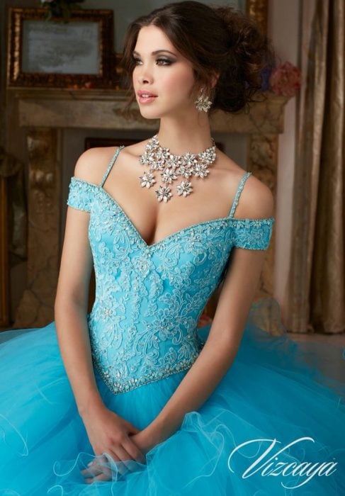 Chica usando un vestido de xv años color azul con tiara y collar de piedras brillantes 