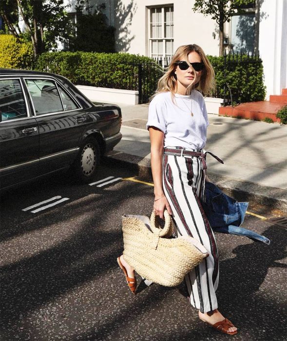 Chica usando un bolso straw handbags con un pantalón a rayas y blusa blanca