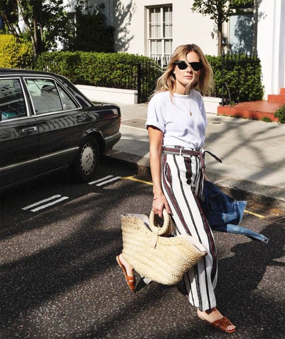 Chica usando un bolso straw handbags con un pantalón a rayas y blusa blanca 