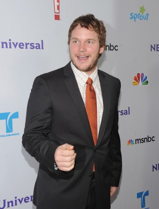 Chris Pratt usando un trajenegro camisa a cuadros y corbata naranja 