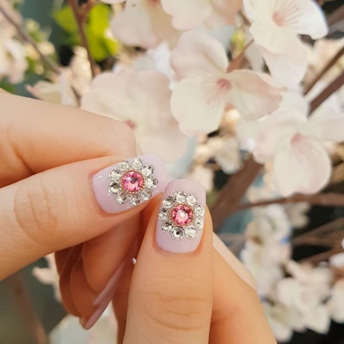 Uñas de vidrio que lucen como diamantes en color lila con piedras rosas 