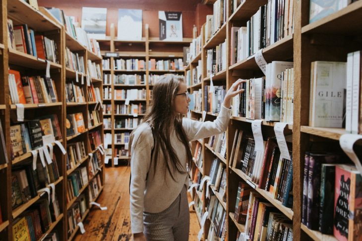 chica dentro de una biblioteca leyendo libros