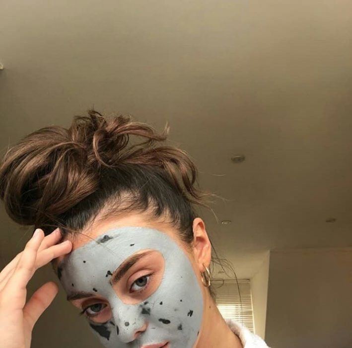 chica usando mascarilla de arcilla gris en su piel 