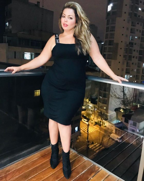 Modelo plus size fluvia Lacerda usando un atuendo de vestido negro con botines 