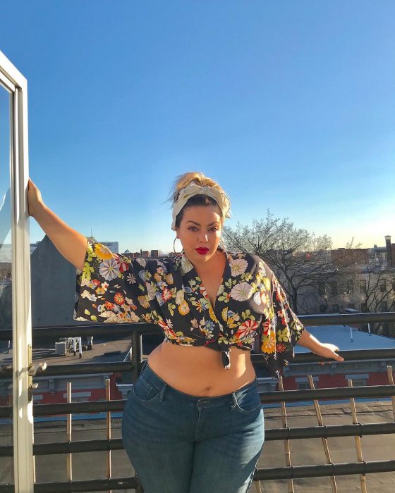 Modelo plus size fluvia Lacerda usando un atuendo de blusa crop top y jeans 