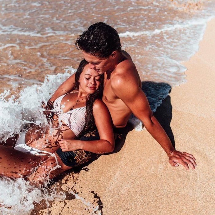 Pareja de novios abrazados besándose mientras están en la playa 