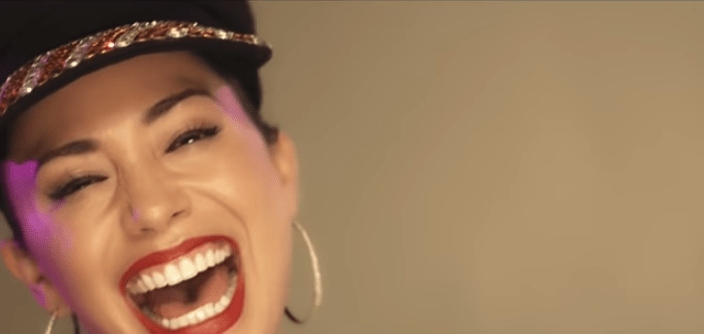 mujer con sonrisa grande gorra y aretes 