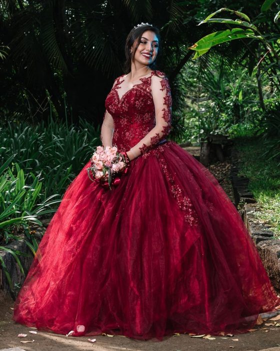 Quinceañera usando un vestido rojo con mangas