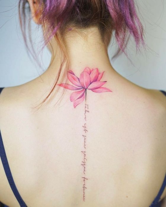 Chica conun tatuaje de espina dorsal con letras y una flor 