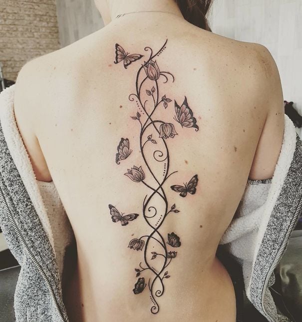 Tatuaje en la espina dorsal con diseño de mariposas enredadas en flores 