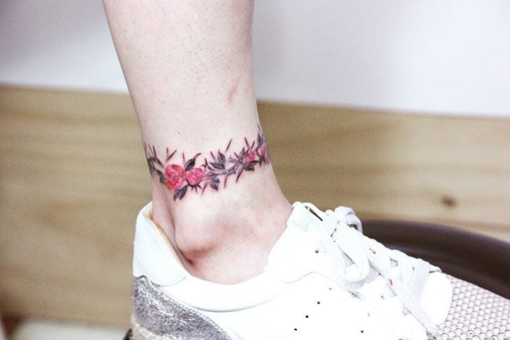 Tatuaje en el tobillo en forma de rosa con espinas 