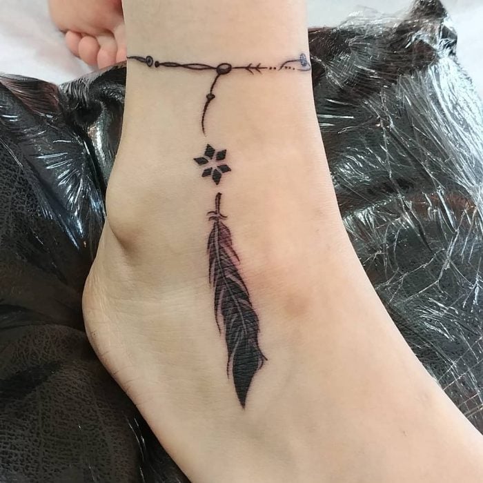 Tatuaje en el tobillo en forma de pulsera con una pluma 
