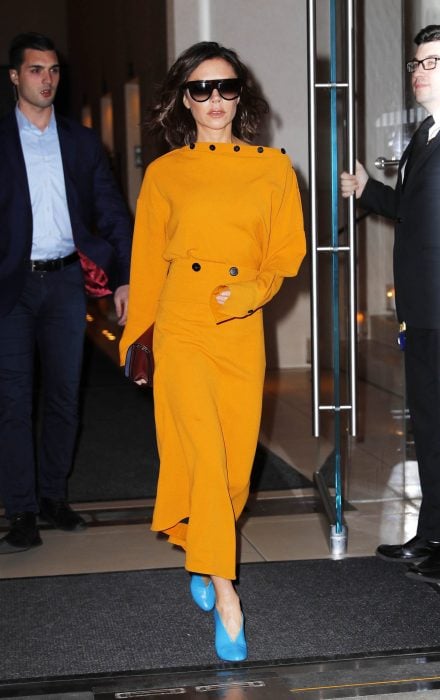 Victoria Beckham con unos zapatos azules y vestido amarillo 