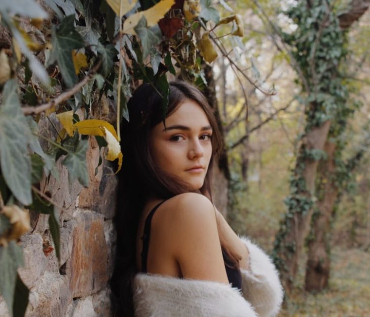 chica con sueter blanco cabello castaño mirando a la cámara 