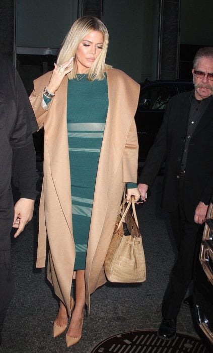 Khloe Kardashian usando un vestido color verde con abrigo beige 