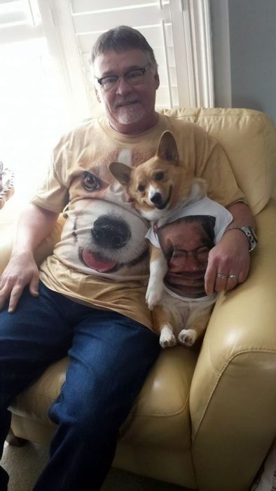 Dueño de un corgi sentado junto a su perro mientras usan playeras con sus rostros 