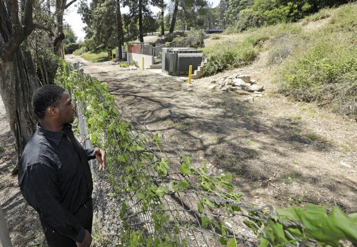 Hombre parado frente a una cerca viendo el lugar donde lo abandonaron de bebé