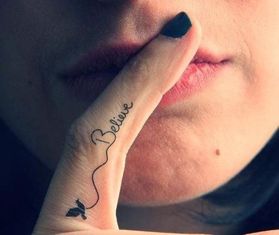 Tatuaje con una inscripción en el dedo medio 