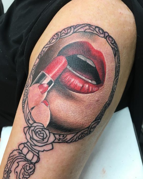 Tatuaje de maquillje con un espejo reflejando a una chica pintarse 