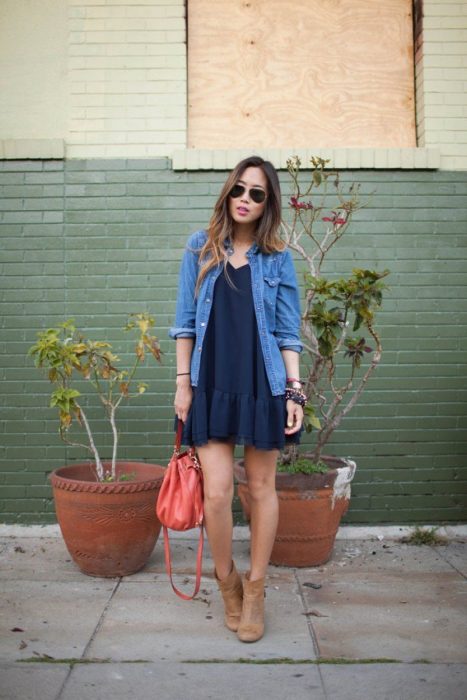 Chica para en la calle usando un vestido azul y bonites café