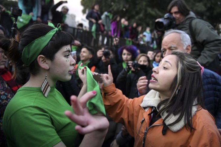 mujer con pañuelo verde y mujer enfrente discutiendo