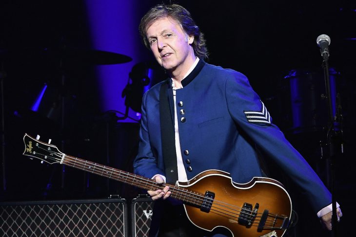 Paul McCarty sosteniendo su guitarra en el escenario 