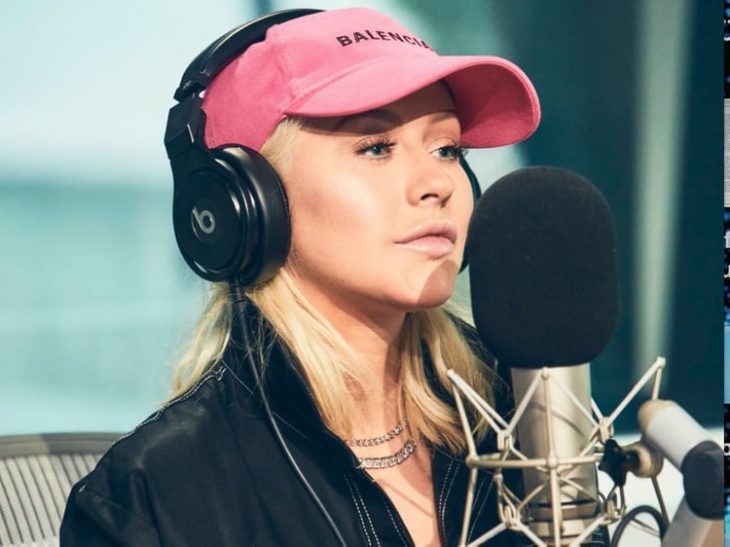 mujer rubia con gorra rosa audifonos y microfono 