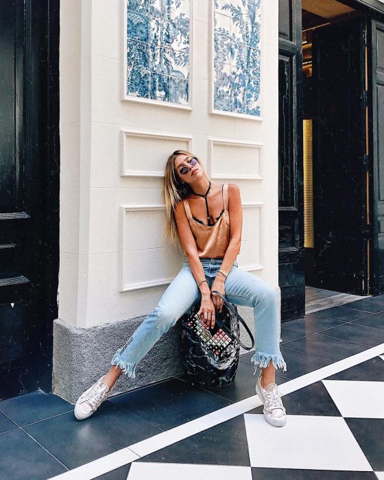 mujer con pantalones de mezclilla y blusa de satin con bralete 