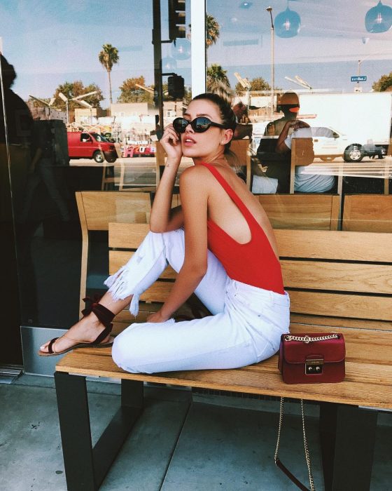 mujer con traje de baño rojo y pantalón blanco 