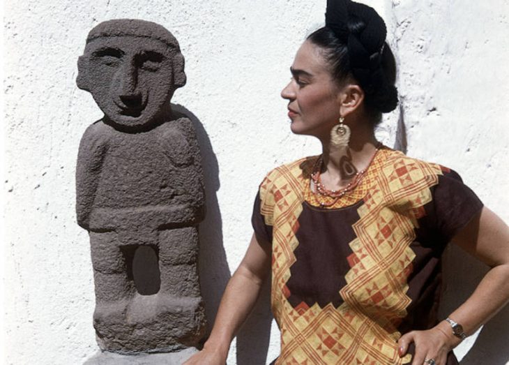 mujer con chongo mirando escultura indigena