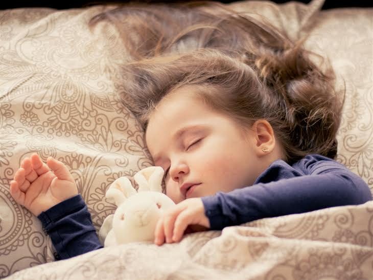 Niña recostada en la cama durmiendo