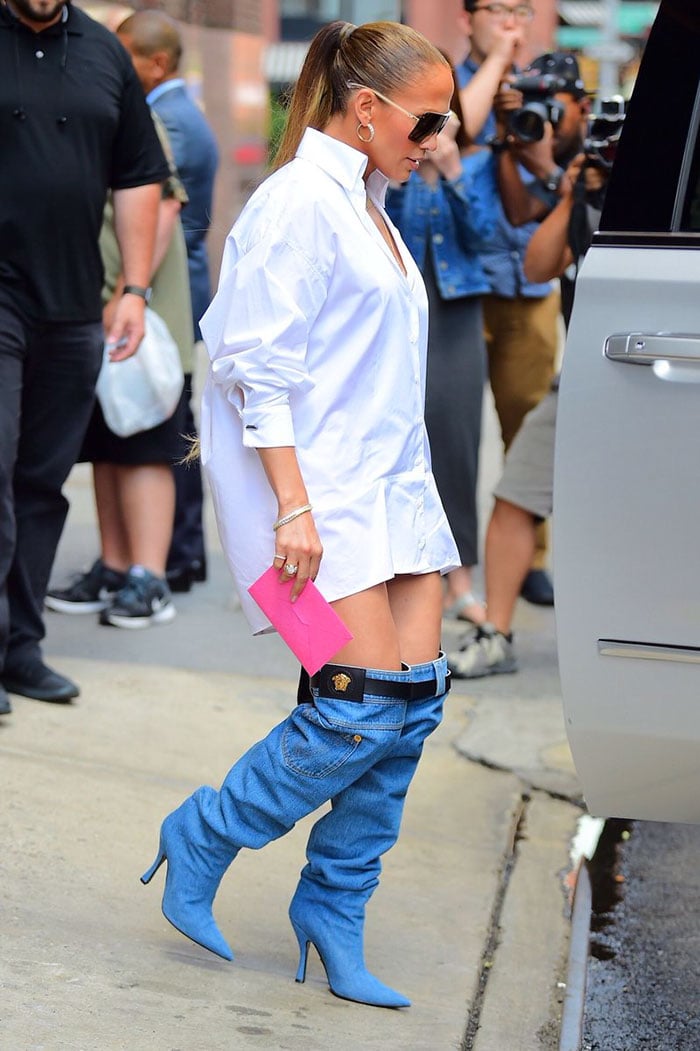 Jennifer Lopez usando una blusa overzise y botas largas 