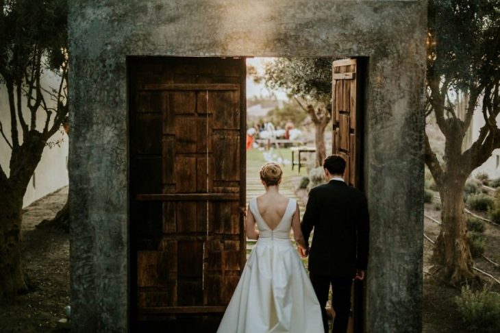 Pareja de novios en un callejón besándose durante una sesión de fotos el día de su boda 