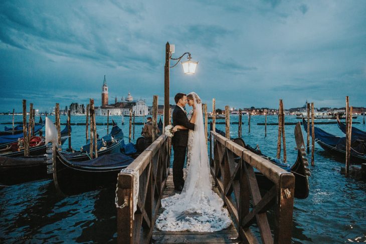 Pareja de novios en un callejón besándose durante una sesión de fotos el día de su boda 