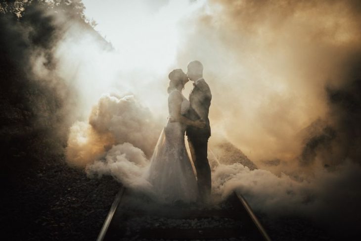 Pareja de novios en un callejón besándose durante una sesión de fotos el día de su boda 