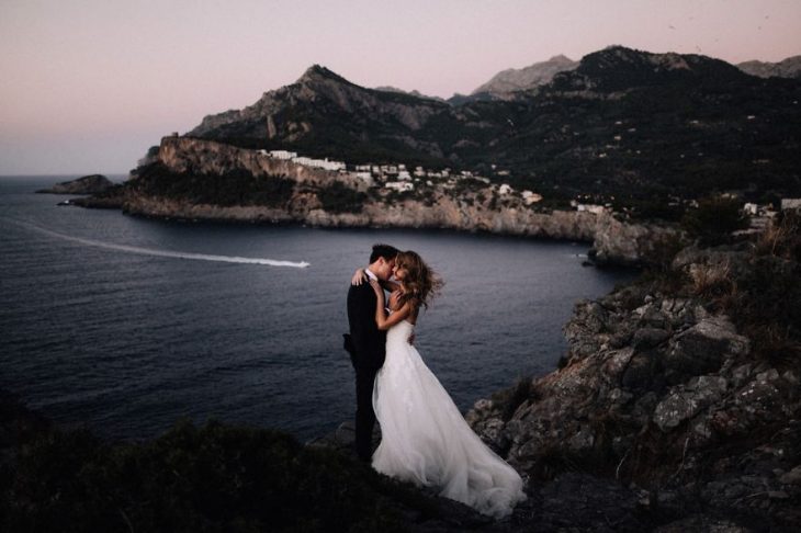 Pareja de novios en un callejón besándose durante una sesión de fotos el día de su boda 