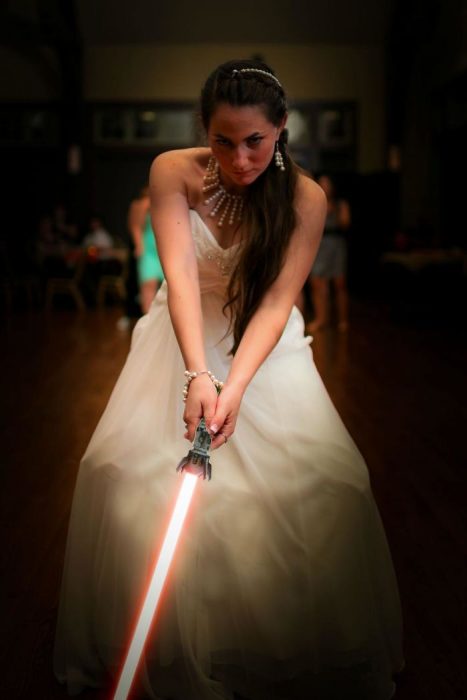 Novia sosteniendo un sable de luz de star wars 