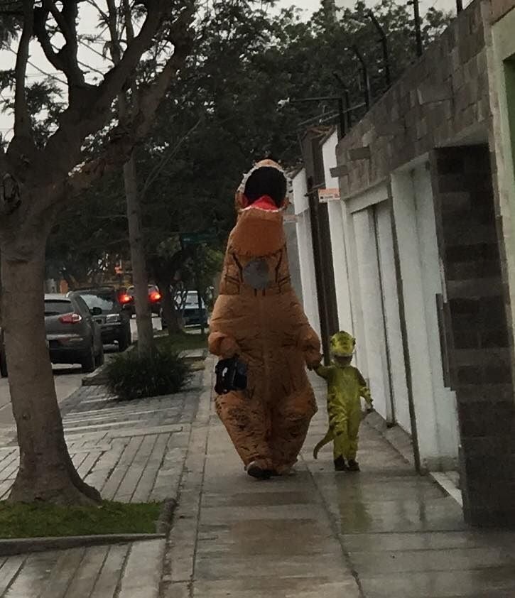 Papá e hijo caminando por la calle vestidos de dinosaurios