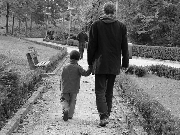 Papá e hijo caminando tomados de la mano por un sendero